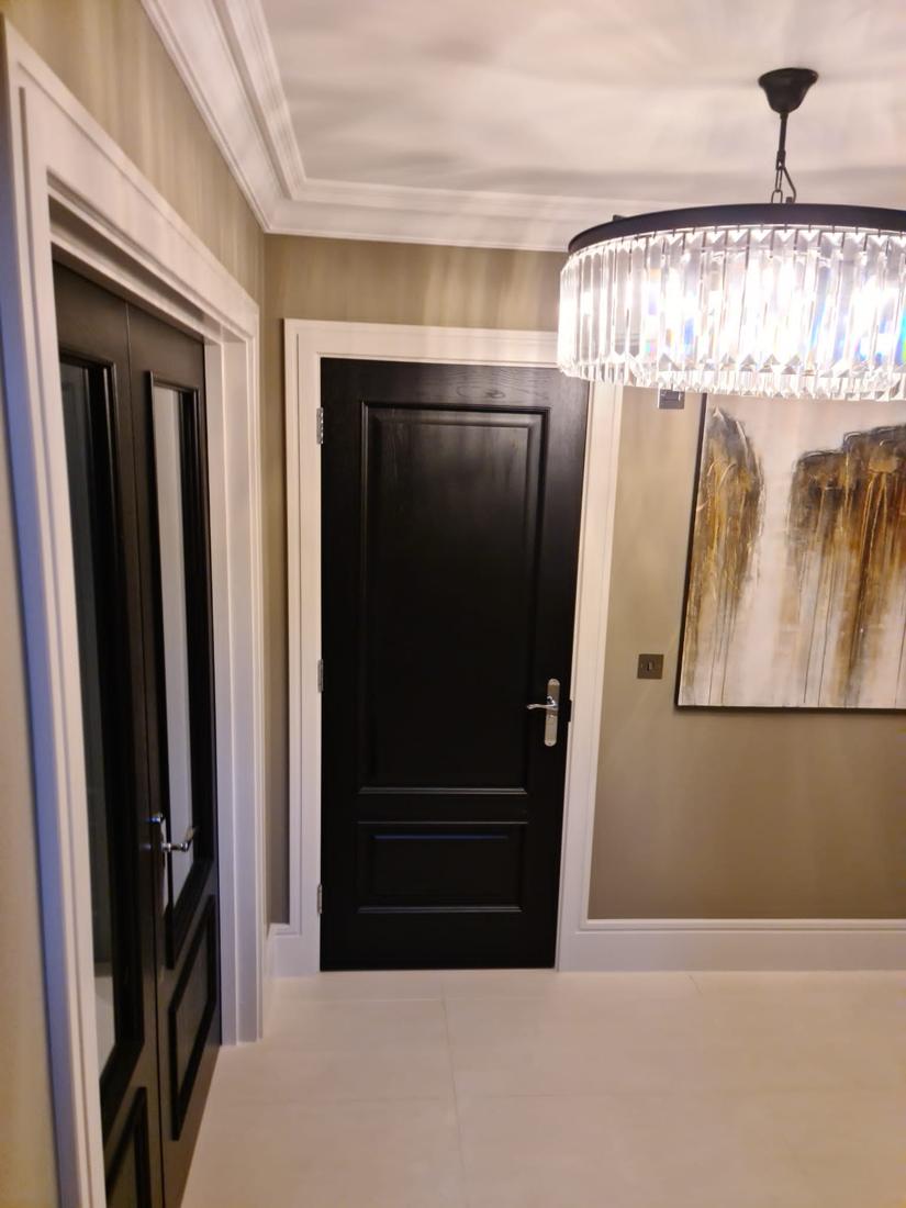 Hallway with black doors and crystal chandelier