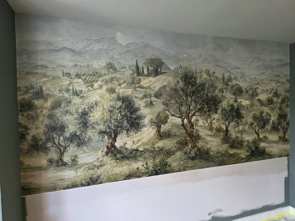 Hand-hung landscape wall mural above white wall panelling